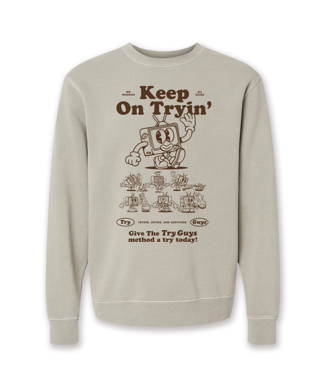 A tan crewneck sweatshirt with a design of a TV character waving printed in brown on the front. Above the character is large text that reads, "Keep On Tryin'". Below the character are different versions of the character in tricky situations, like the tv guy slipping on a banana. Below those designs is text that reads, "Give The Try Guys method a try today!" From the Try Guys.