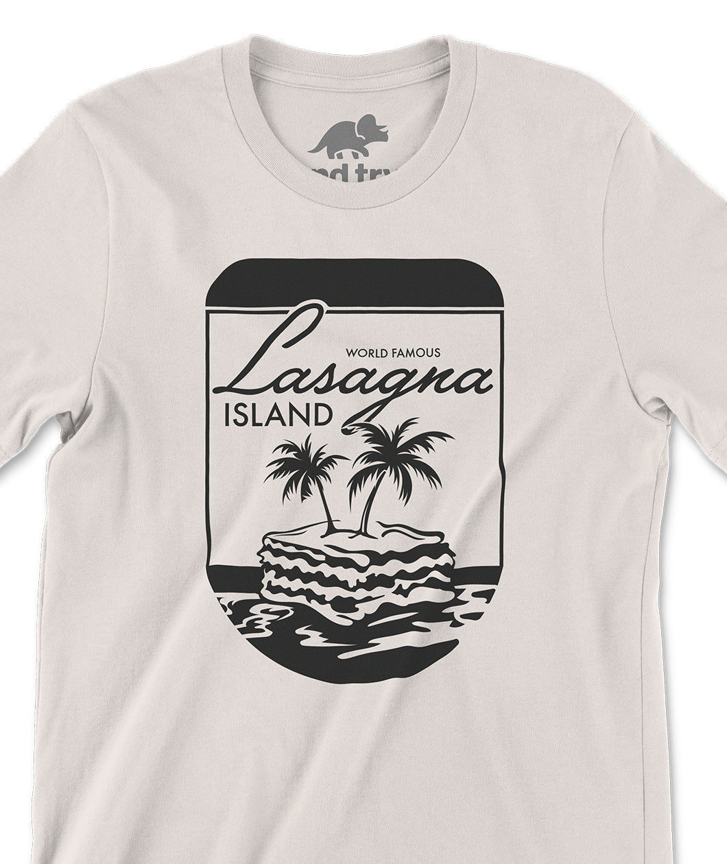 A closeup of an off-white shirt with a design printed in black on the front. The design is of a round, pill-shaped border with a lasagna floating atop the sea. Two palm trees are sprouting from the lasagna. Above the is text that reads "World Famous Lasagna Island." From the Try Guys.