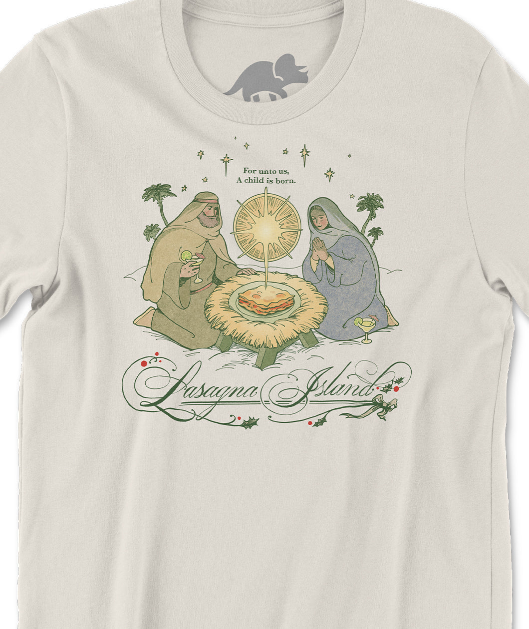 A closeup of natural white t-shirt with a textured illustration printed on the front. The illustration shows Joseph and Mary kneeling in front of a manger containing a plate of lasagna. The text reads "For unto us, a child is born. Lasagna Island" From the Try Guys.