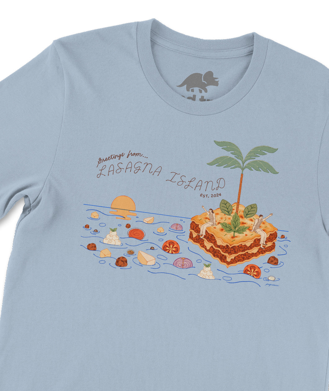 A closeup of a blue t-shirt with a design on the front. The design is an illustration of two people sitting on a floating lasagna island. Surrounding them is an ocean filled with lasagna ingredients like tomatoes, onions, cheese, and more. Next to the illustration is text that reads, "Greetings from Lasagna Island, est. 2024". From the Try Guys.