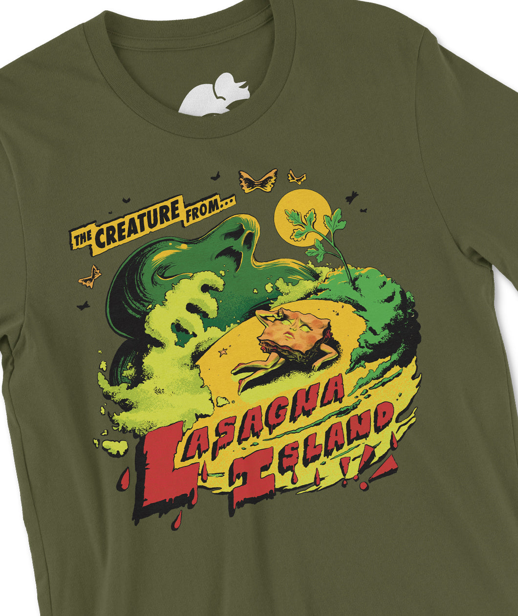A closeup on an olive green t-shirt with a textured illustration printed on the front. The illustration shows a watery monster looming over an anthropomorphized lasagna woman collapsed on a beach. The text reads "The Creature From... Lasagna Island!!!" From the Try Guys.