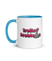 A white ceramic mug with a blue handle and interior. The mug has a design of the Trolley Problems logo. From the Try Guys.