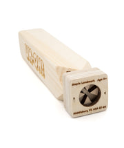 A wooden train whistle with the phrase "UH-OH!" engraved on one side. From the Try Guys.